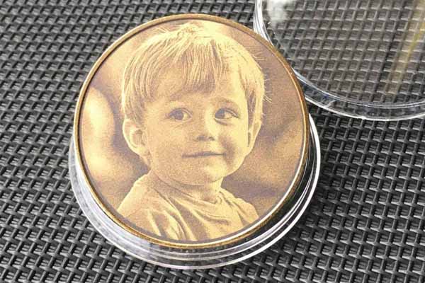 Coin with dot-engraved portrait of a smiling child in a clear case