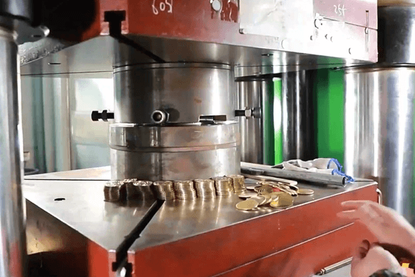 Coins being pressed by a hydraulic machine during minting