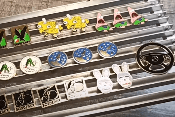 Completed DIY enamel badges on a rack