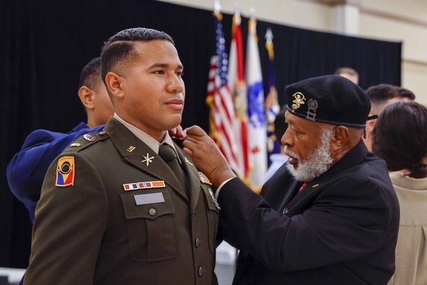 Senior veteran pinning a medal on a young military officer in uniform